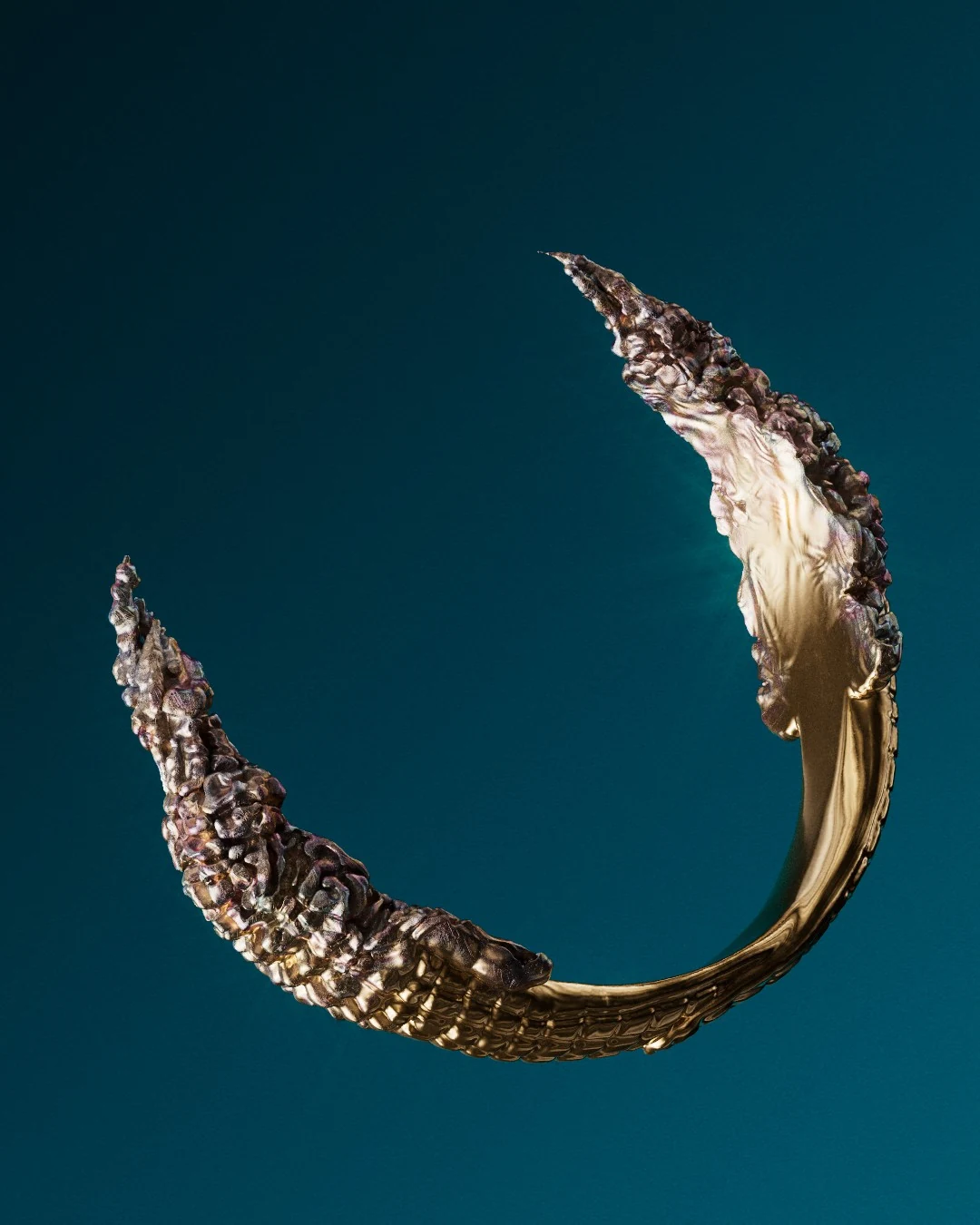 The ring’s open form, suspended against teal.